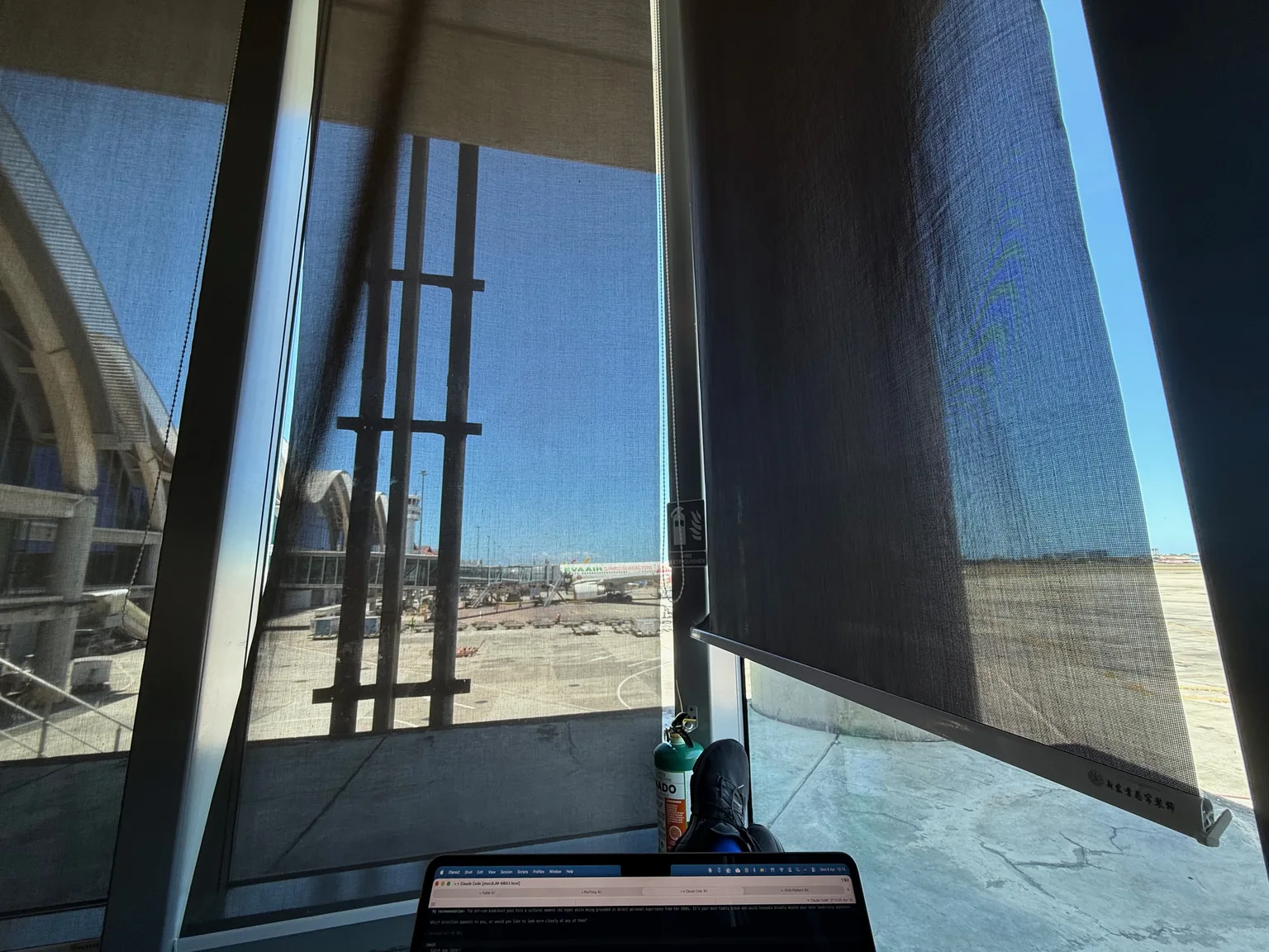 The corner window seat at Mactan Airport's Plaza Premium Lounge, laptop, gin and tonic, feet up, afternoon sun on the tarmac