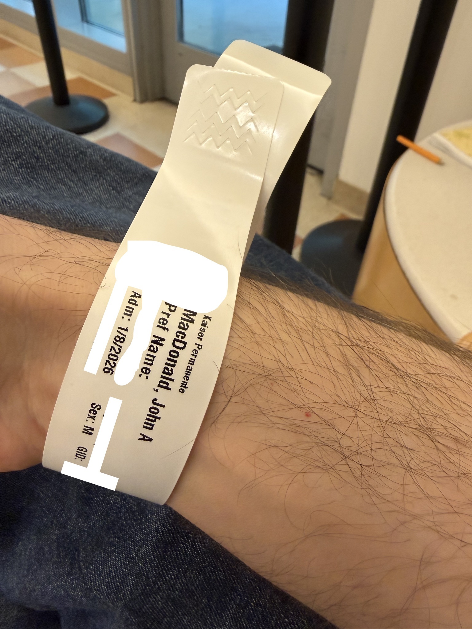 Hospital admission wristband worn during treatment, showing patient and visit identifiers.